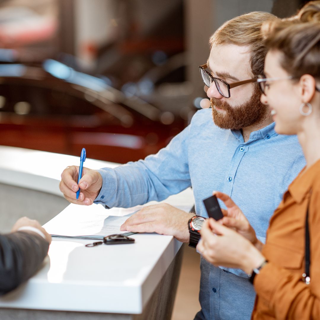 Dos personas firmando propiedad de coche